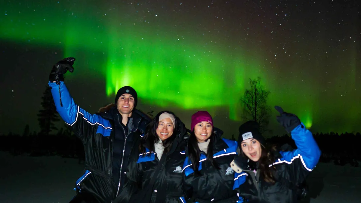Small group of eight beside a 4x4 van photographing the northern lights on a private aurora borealis tour Rovaniemi operators run, Lapland